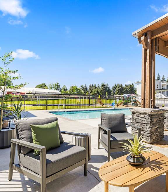 A wooden table with a potted plant on it sits in the middle of a patio.