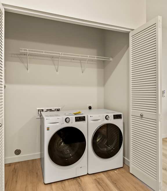 A laundry room with two washing machines and a dryer.