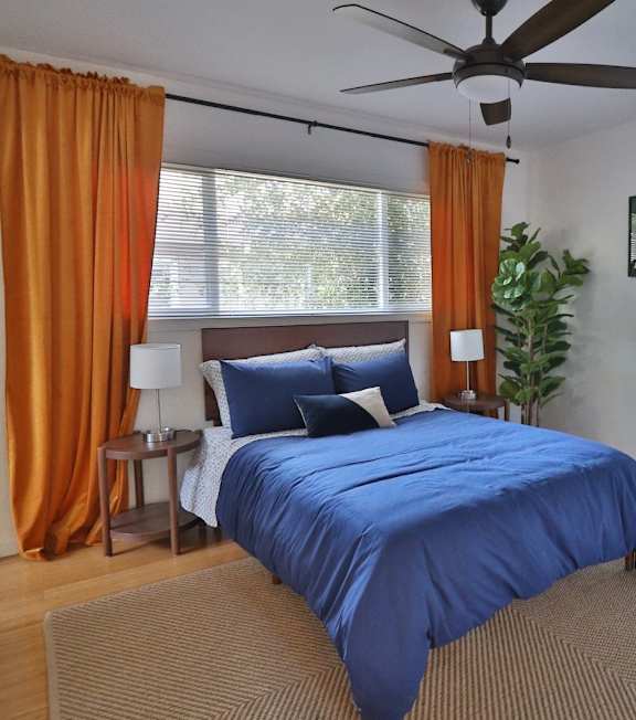a bedroom with a blue bed and a ceiling fan