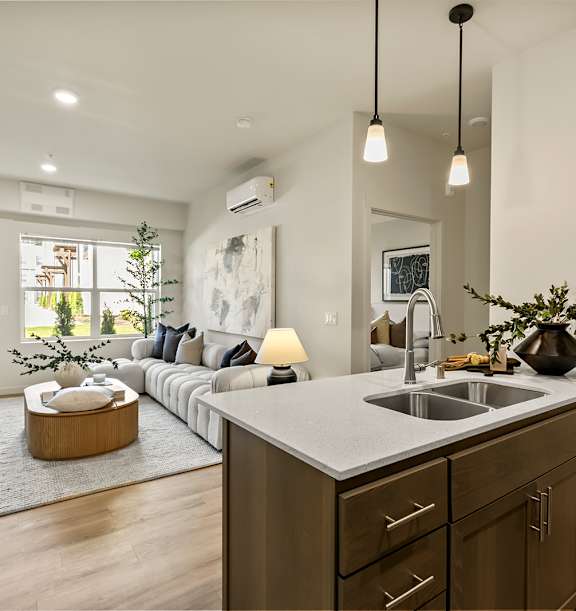 A modern kitchen with a large island and a living area with a couch and a coffee table.