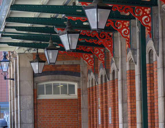 A row of red brick pillars with white trim and a row of hanging lights.