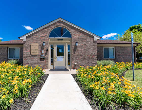 the front of a brick church with yellow flowers