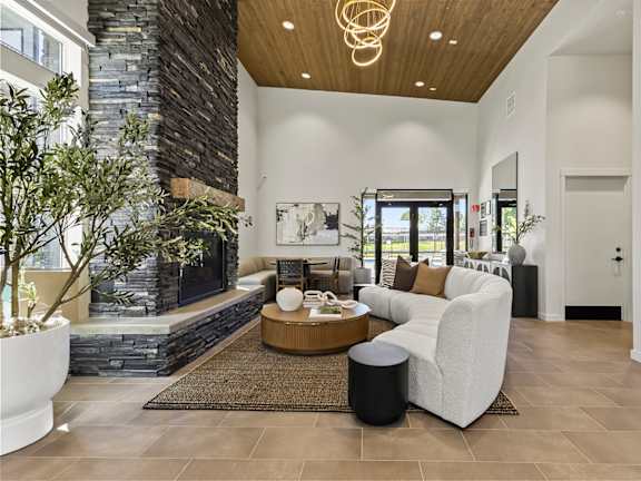 A modern living room with a stone fireplace and a large window.