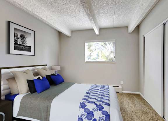 A bedroom with a bed, pillows, and a window. at Park at Fitzsimons Apartments, Aurora, Colorado