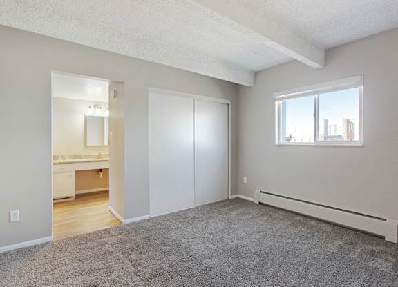 A room with a grey carpet and a window. at Park at Fitzsimons Apartments, Aurora, MO