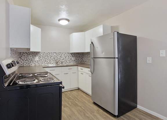 A kitchen with a black stove top oven and a silver refrigerator. at Park at Fitzsimons Apartments, Colorado