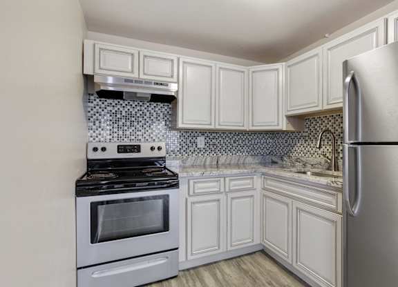 A kitchen with white cabinets and a stainless steel refrigerator. at Park at Fitzsimons Apartments, Aurora