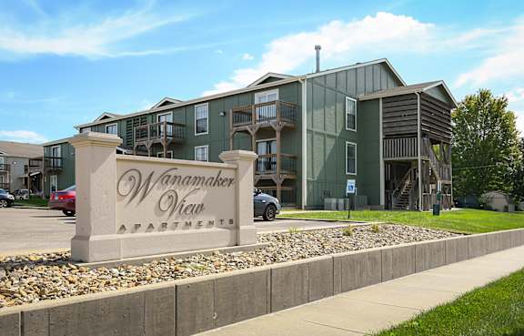 A large building with the name Wanamaker View Apartments on a stone pillar in front.