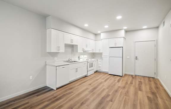 a kitchen with white cabinets and white appliances and a wood floor