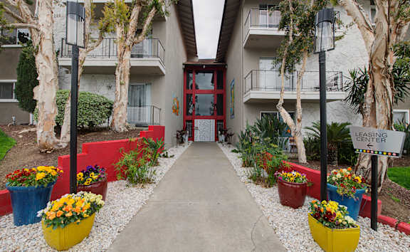 a walkway with flowers and trees in front of an apartment building at Dwell Apartment Homes, California, 92507