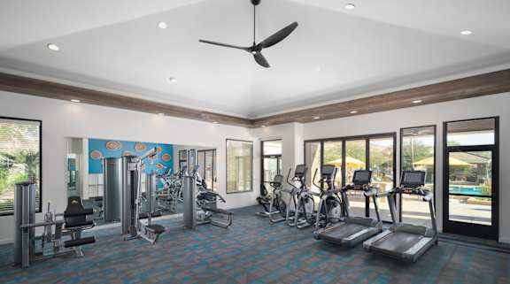 A spacious gym with a variety of equipment and a ceiling fan.