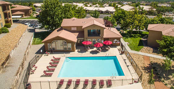 A large house with a pool and a patio with red chairs at West Park Apartments, New Mexico 87114