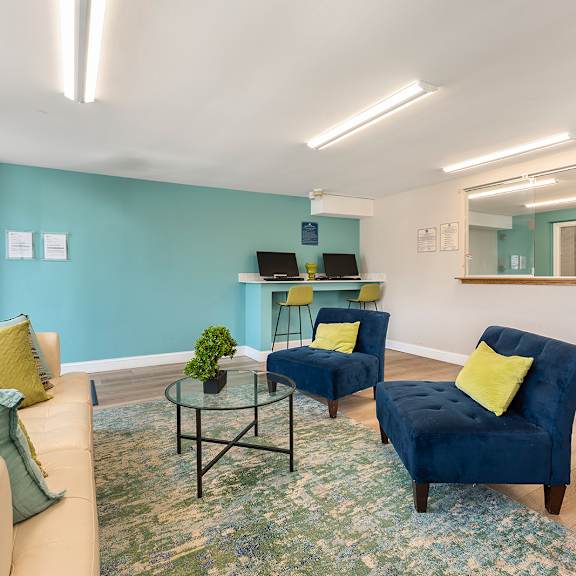 a living room with couches and a table and a clock on the wall