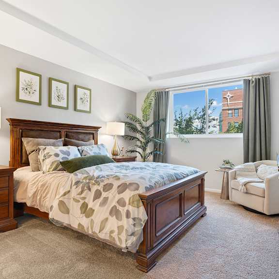 A bedroom with a large bed and a chair.