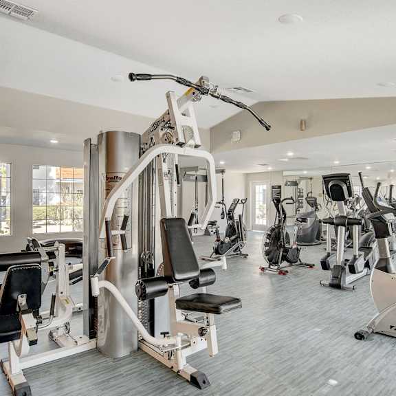 A gym with a variety of equipment including treadmills, weights, and exercise machines.