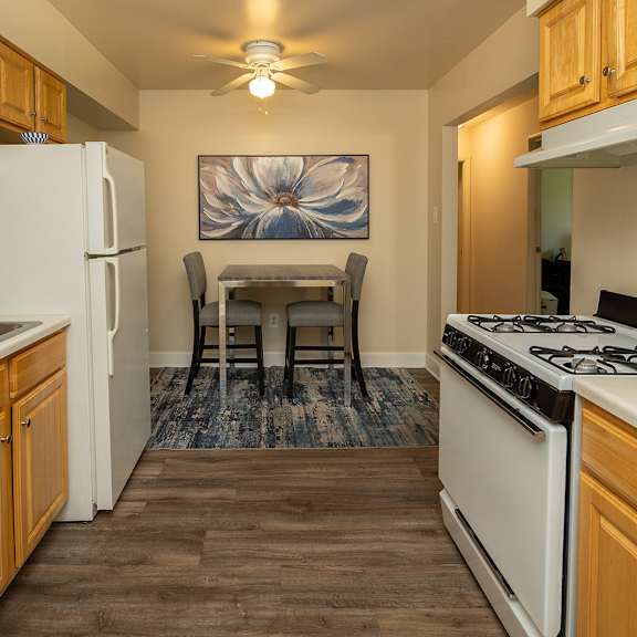 a kitchen with white appliances and wooden cabinets at Deer Park Apartments, Randallstown Maryland