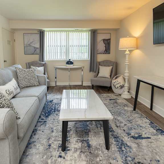 a living room with a blue couch and a tv at Deer Park Apartments, Randallstown, MD 21133