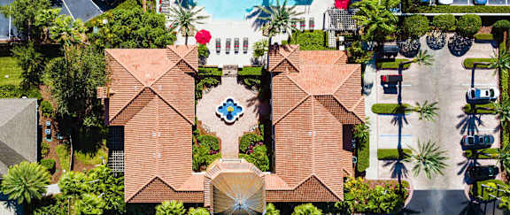 Stunning aerial view of the community clubhouse and sparkling resort-style pool surrounded by palm trees.