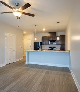 A spacious kitchen and living room with wood flooring and modern appliances.at Hawthorne Pointe, Bondurant, IA
