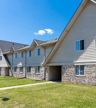a row of houses with grey siding and a green yard