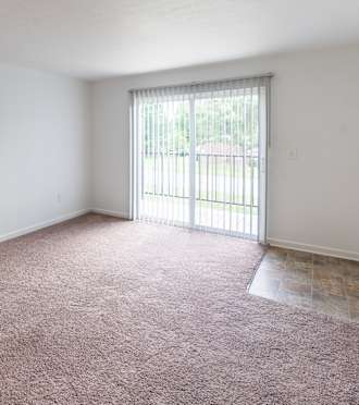 A room with a carpeted floor and a window with blinds  at Tymberwood Trace Apartments, Louisville, KY.