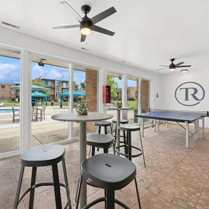 A room with a pool outside the window and a table with chairs.