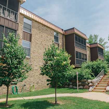 A building with a brown brick exterior and a green lawn in front. at Astor Place of Edina Apartments , Minnesota