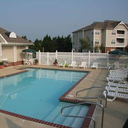 A swimming pool surrounded by a white fence and chairs.