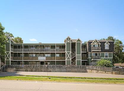A large building with a green facade and a sign that reads "Apartments".