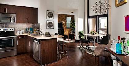 A modern kitchen with dark wood floors and stainless steel appliances.