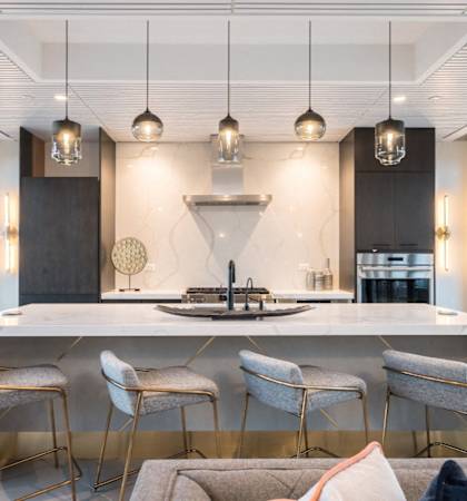 A modern kitchen with a large island and chairs.