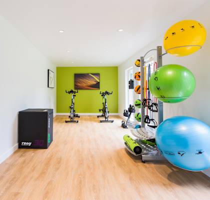 a home gym with weights and other exercise equipment in a white room with a green accent wall