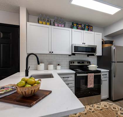 A kitchen with white countertops and a black refrigerator.