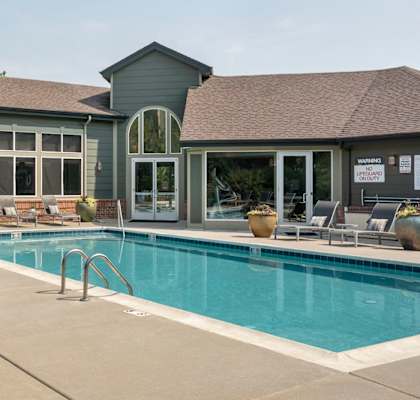 A pool area with a table and chairs outside a house.