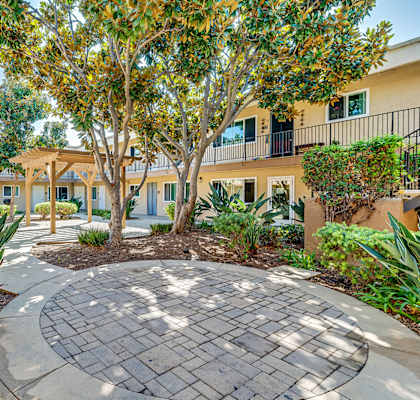 A courtyard with a circular paved area surrounded by buildings and trees.