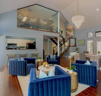 A living room with blue couches and a glass staircase.