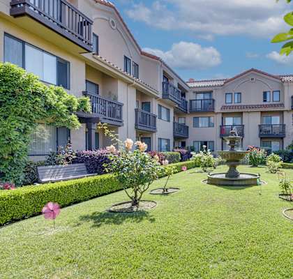 a yard with a fountain in the middle of some apartments