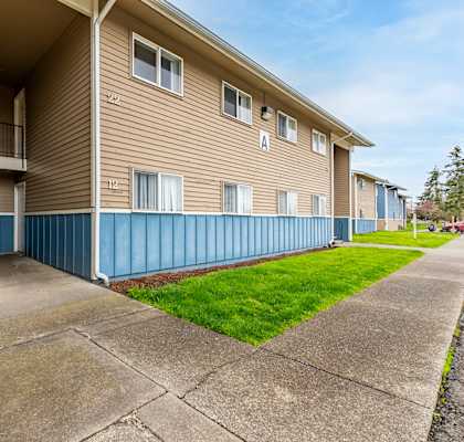 Apartment building with a blue stripe on the side and a staircase leading to the second floor.