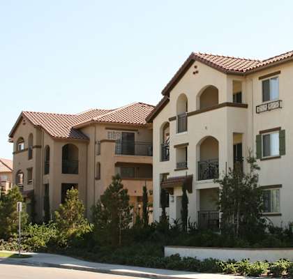 A large beige building with a red tile roof and balconies.