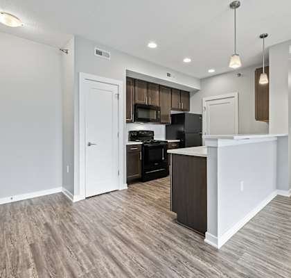 A kitchen with white walls and a wooden floor.