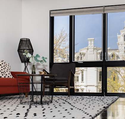 a living room with a red couch and a black and white rug