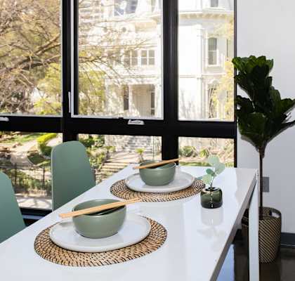 a dining table with two bowls and two chopsticks on it in front of a large window