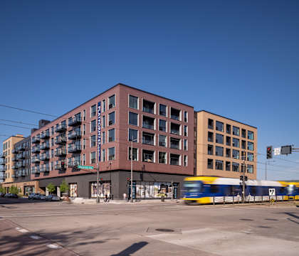 a city block with a train on the tracks in front of it