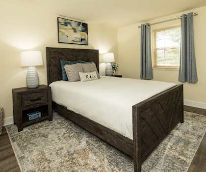 A bedroom with a large bed and a painting on the wall.