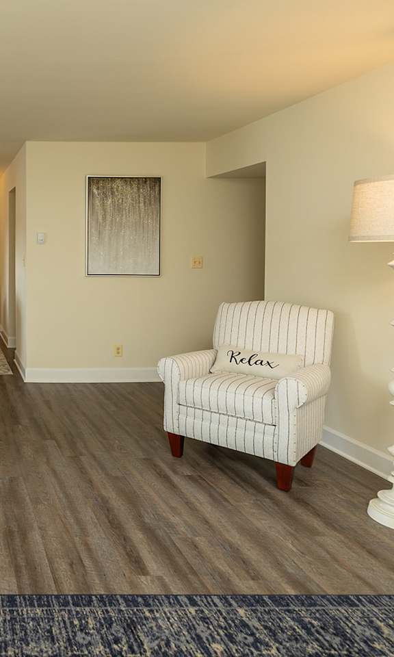 A living room with a chair and a lamp at The Brittany Apartments, Pikesville, MD, 21208
