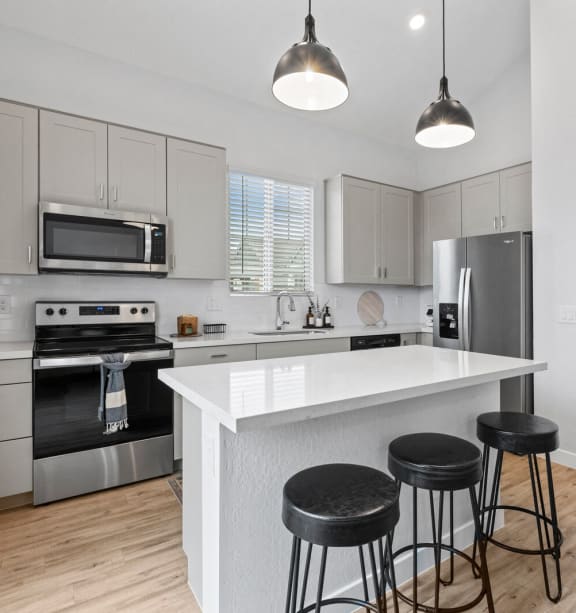 a kitchen with a large island with three stools at Village of Chandler, Chandler Arizona