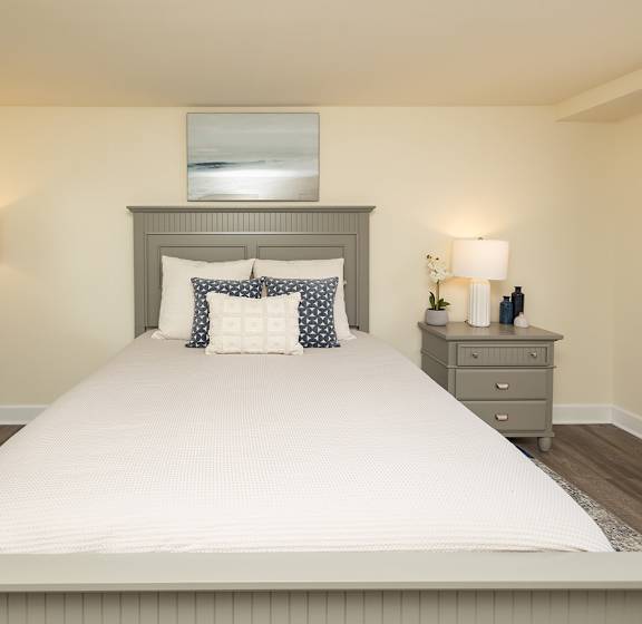 A bedroom with a large bed, two nightstands, and a mirror. at Colony Hill Apartments & Townhomes, Baltimore
