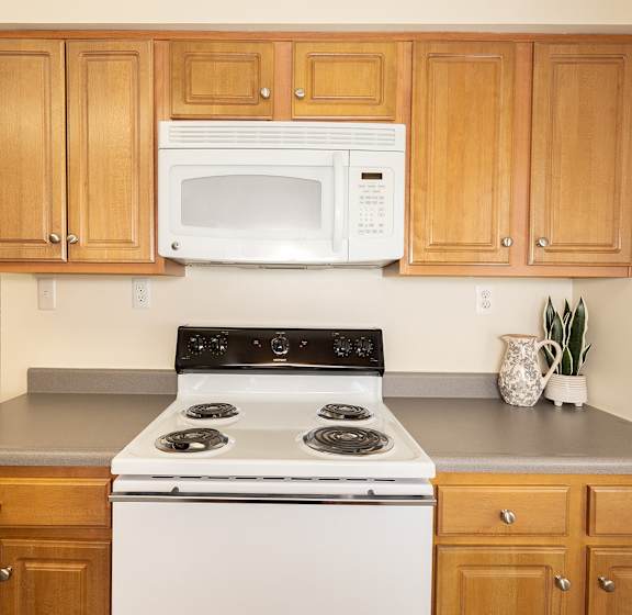 A kitchen with wooden cabinets and a white stove top oven.