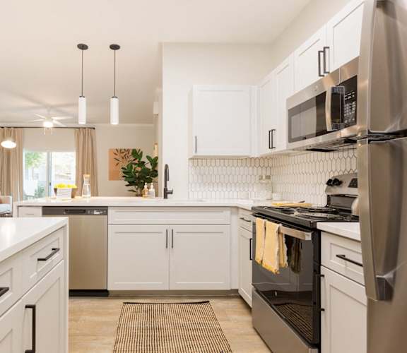 a white kitchen with stainless steel appliances and white counters
