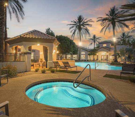 a swimming pool at night with a house and palm trees
